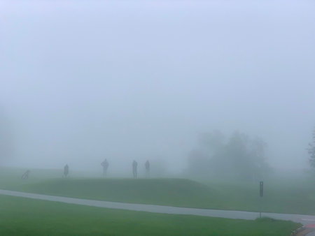 Golfer Teeing Off on Crans Sur Sierre Golf Course with Fog in Crans Montana in Valais, Switzerland.の写真素材