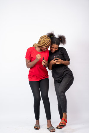 two young black women feeling excited and happy viewing content on a phoneの写真素材