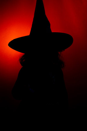 Silhouette of a little witch with her wand on Halloween