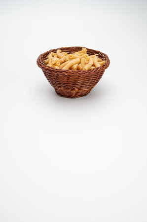shot of italian torchiette pasta in a wicker canister on a white color backgroundの写真素材