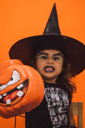 Little Caucasian witch with her Halloween pumpkin in her handの写真素材