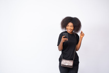 beautiful african lady viewing content on her phone looking excited and happyの写真素材