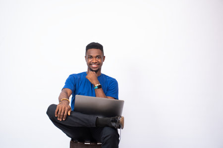 portrait of a young black man sitting with his laptop computer