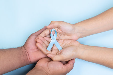 two hands holding light blue ribbon, prostate cancer, light blue background