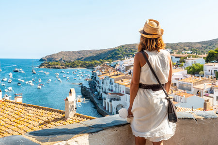A young woman on vacation looking at the city of Cadaques from a viewpoint, Costa Brava of Catalonia, Gerona, Mediterranean Sea. Spainの写真素材