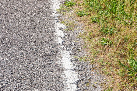 Close up of a asphalt road along green grassの写真素材