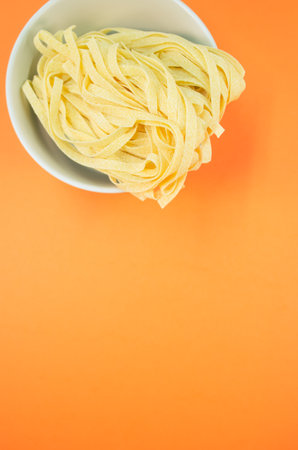detail view of a bowl of cooked pasta on orange background with copy spaceの写真素材