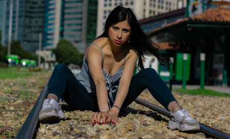 beautiful Colombian woman in a train station waiting for the wagon playing on the tracksの写真素材