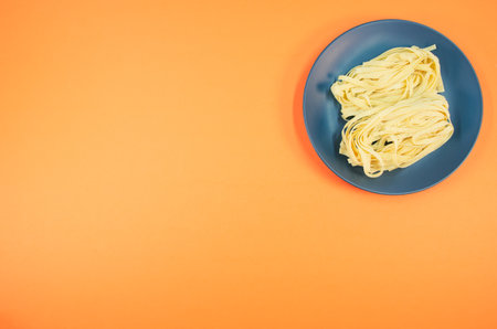 detail view of a bowl of cooked pasta on orange background with copy space
