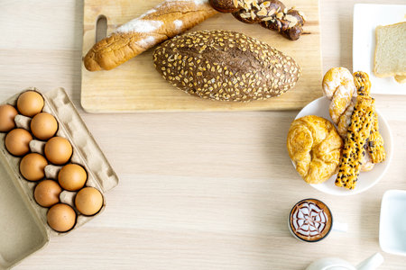Fresh homemade baked bread with butter served as breakfast on white table with boiled eggs and milk...