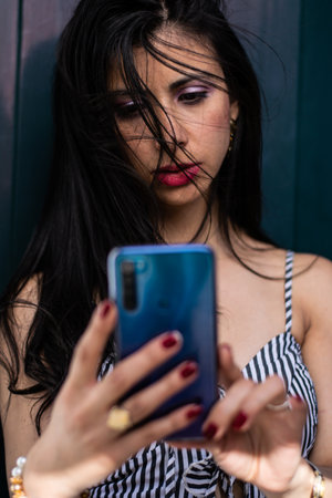 Beautiful Colombian woman with sunglasses checking her cellphoneの写真素材