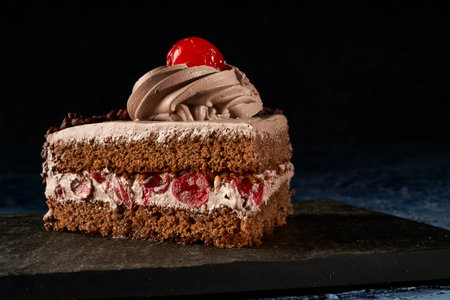 slice of chocolate cake filled with cream and cherries