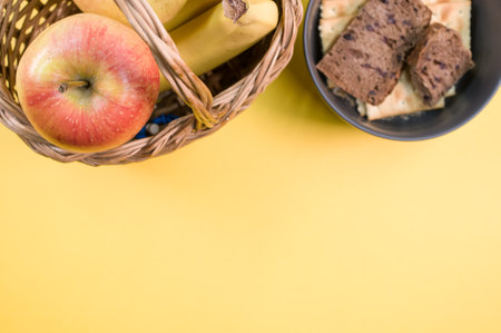 Fresh and healthy fruits and bowl of fresh bread on yellow surface - apples bananas with text spaceの写真素材