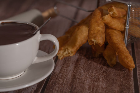 cup of hot chocolate with freshly made churros on wooden background typical spanish breakfast on holidaysの写真素材