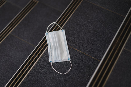 A used protective facemask scattered and unwell-managed in the buildingの写真素材