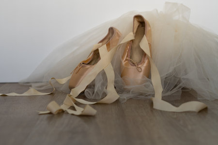 ballet slippers with orange ribbon on a wooden floor and white background
