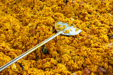 detail of a giant paella from a catering company with its cooking paddle.の写真素材
