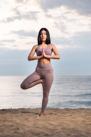 Young woman practicing yoga at the beach at sunrise. Healthy lifestyle. Mind and body exercise