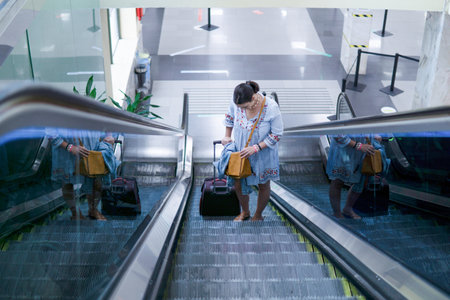 Beautiful Caucasian woman going up the escalator in the airport with a hand luggageの写真素材