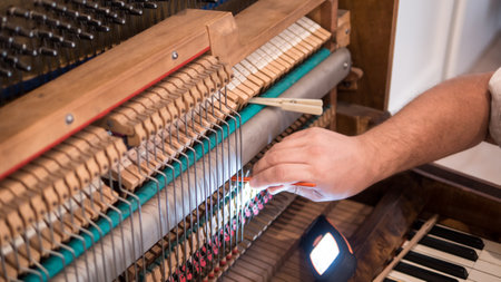 Hands of professional worker repairing and tuning an old english bayonet pianoの写真素材
