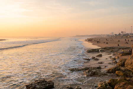 Beautiful sunset in the Atlantic ocean in Portugal and families enjoying on the beach on a sunny dayの写真素材