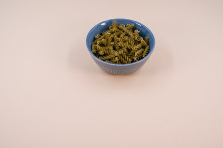 Vertical shot of  italian fusilli pasta in a blue bowl on a beige background with text space