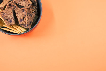 salty crackers with slices of organic brown bread in the bowl on an orange background surfaceの写真素材