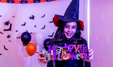Halloween party with a girl holding a Happy Halloween sign in handの写真素材