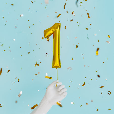 white hand holding a balloon with the number 1 and golden confetti falling down. birthday celebration. 3d renderの写真素材