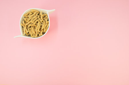 shot of italian torchiette pasta in a white bowl on a pink color backgroundの写真素材