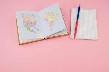A top view of a two-sided pen and a notebook on a pink surface with text space