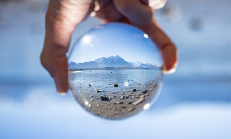 Lake landscape in crystal ball on a sunny day with mountains in the background