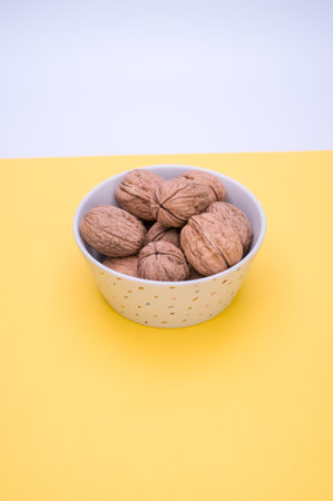 Shot of whole walnuts in a bowl  isolated on a yellow background with text spaceの写真素材