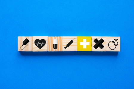 Concept of health insurance, medical symbol in wooden blocks, blue backdrop, copy space