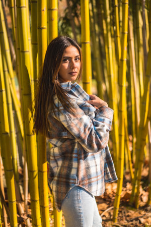 Autumn lifestyle, young Caucasian brunette girl in a plaid wool sweater in a bamboo forestの写真素材