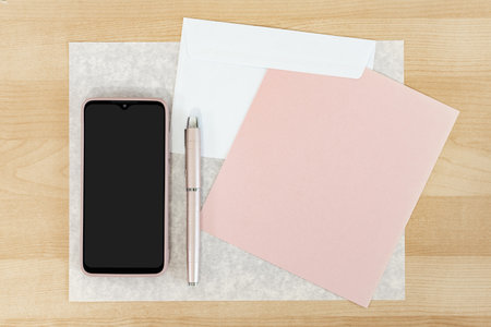 Mockup of cellphone and business card at wooden desk background.