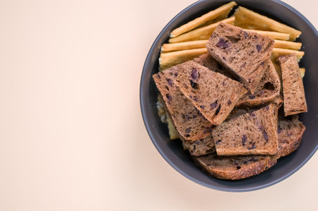 salty crackers with slices of organic brown bread in a bowl on a beige background surface