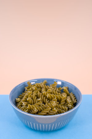 Vertical shot of  italian fusilli pasta in a blue bowl on a blue background with text spaceの写真素材