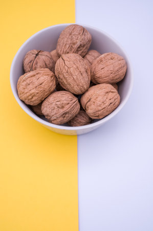 Shot of whole walnuts in a bowl  isolated on a yellow background with text space