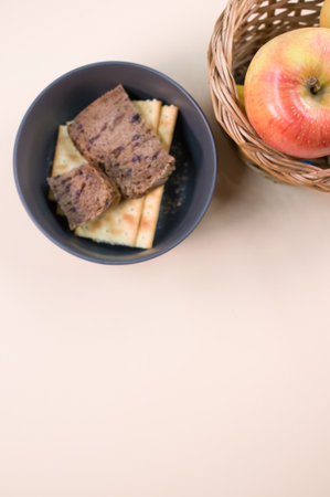 A top view of fruit in a basket with bread in a bowl on a beige surface