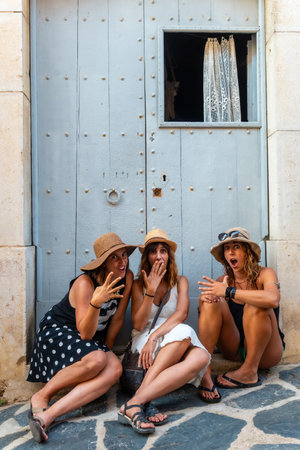 Girlfriends in summer enjoying the holidays. Three friends sitting on a wooden door in the Mediterranean. Spainの写真素材