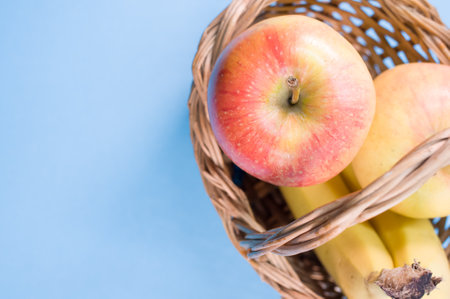 Fresh and healthy fruits on blue surface - apples and bananas with text spaceの写真素材