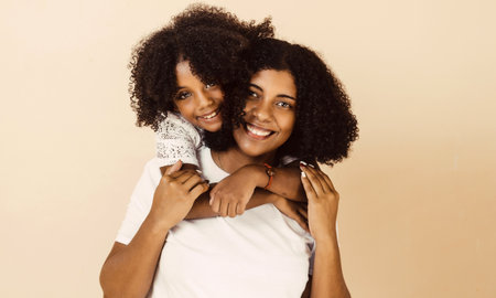 afro american mother and daughter smiling happy hugging over isolated background.の写真素材