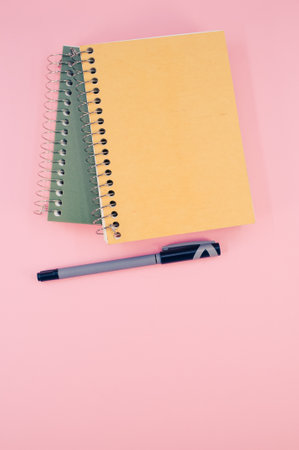A vertical shot of closed notebook on a pink background with copy spaceの写真素材