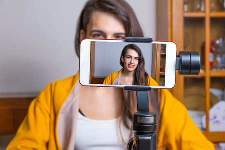 Happy female vlogger live streaming from living room using smartphoneの写真素材