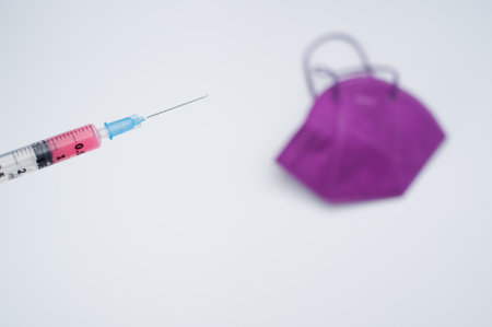 Isolated FFP2 respiratory mask with syringe on a white background wit text spaceの写真素材