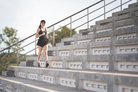 A healthy adult Asian woman running up on concrete stairs of the city stadium to strengthen bodyの写真素材