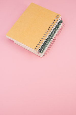 A vertical shot of closed notebook on a pink background with copy spaceの写真素材