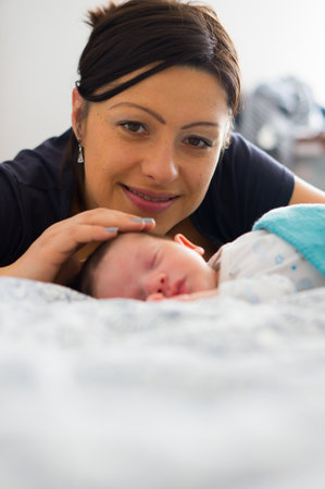 Mother sitting close by her sleeping babyの写真素材