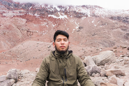 Young man meditating on the mountain, enjoying nature around him.